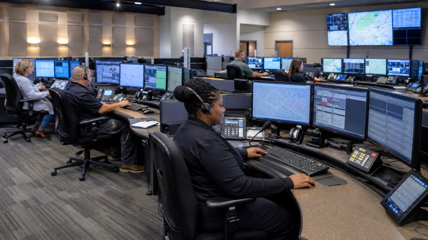 Emergency Communications Center room with dispatchers sitting at dispatch consoles